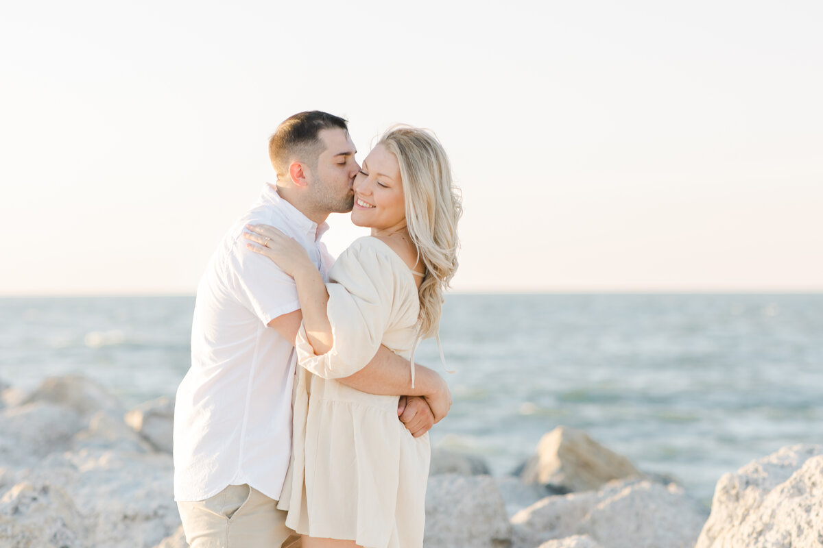 engaged couple kissing on the beach