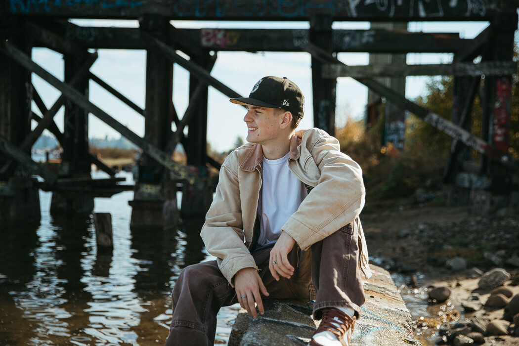 Senior boy sitting on a cement block by the water in Olympia WA