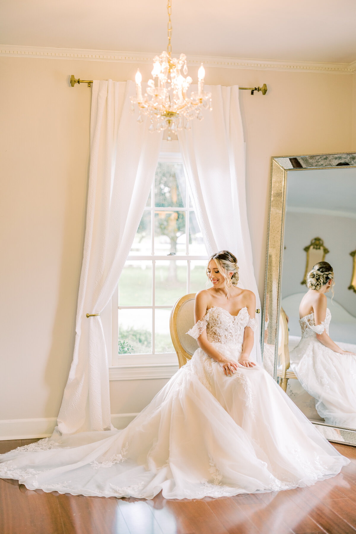 Bride sitting on chair in front of mirror