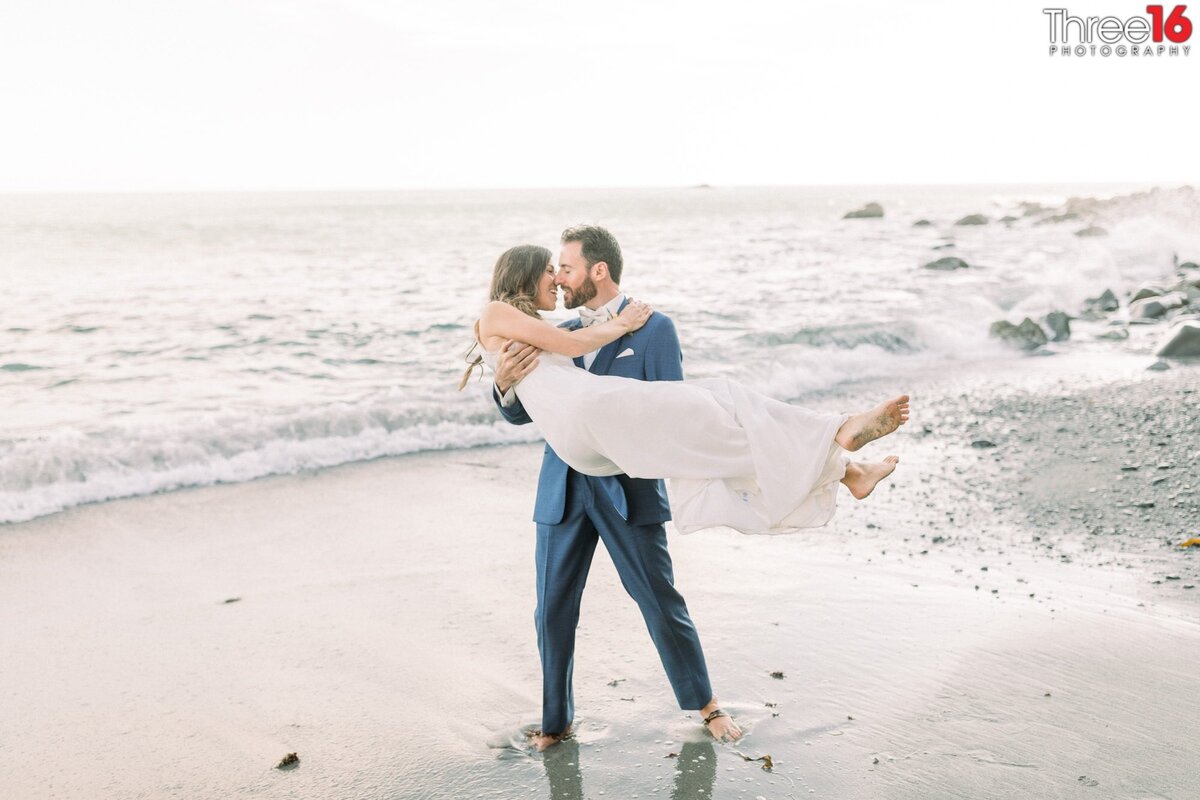Groom lifts Bride after Minimony Celebration on the wet sands along the beach