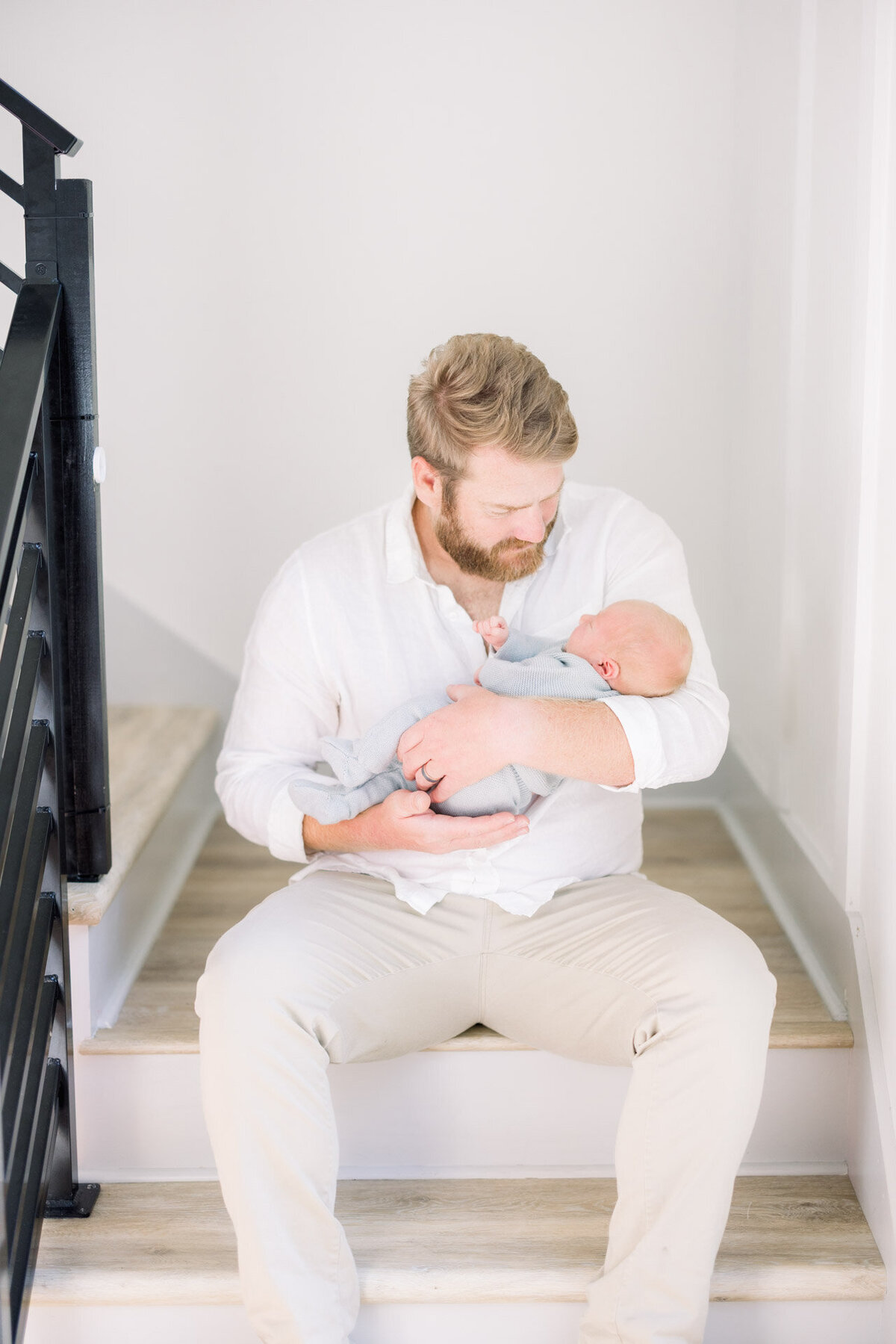 dad holding baby on stairs for Tampa newborn photographer Tina Marie Studio.