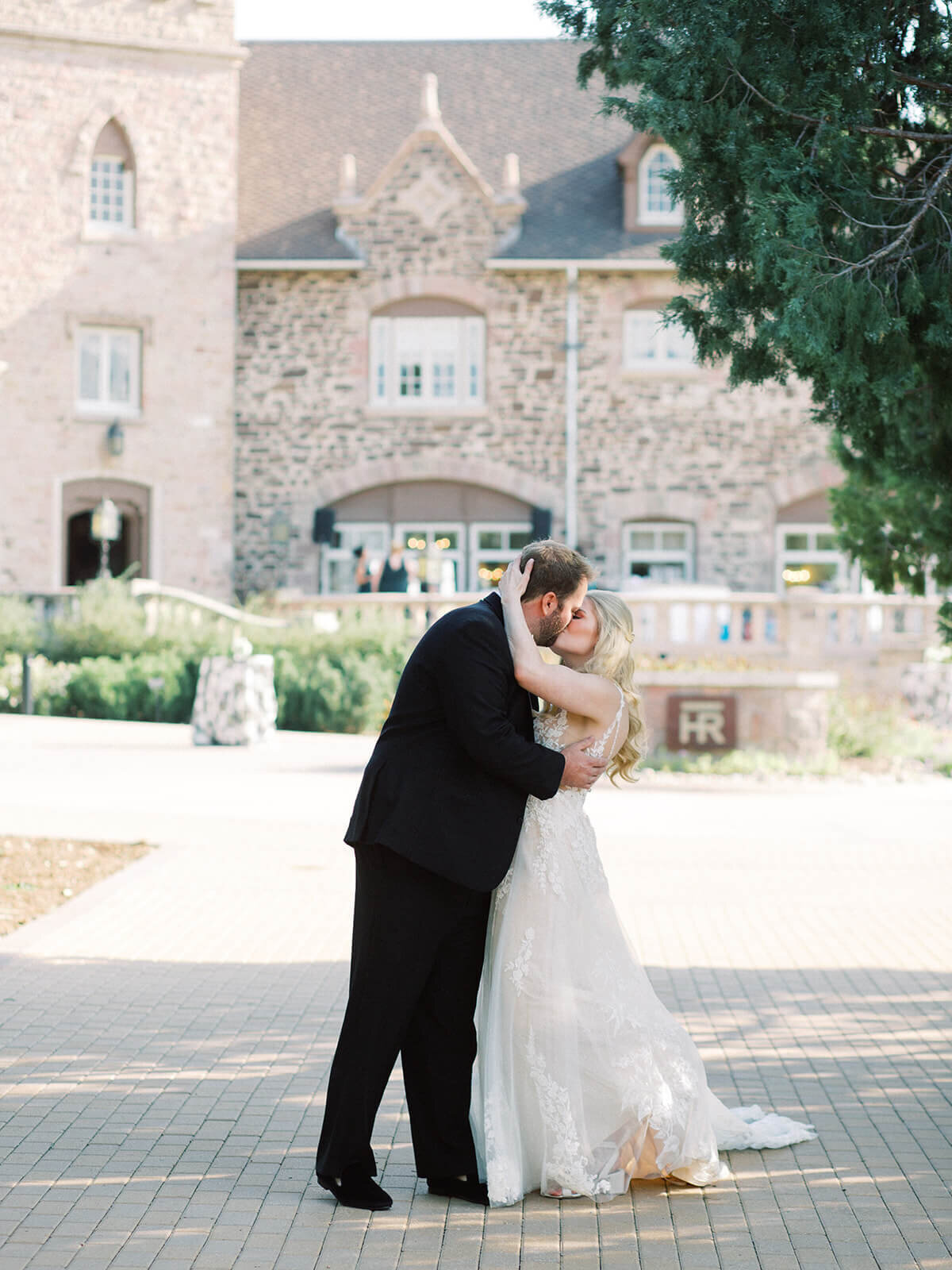 Bride and groom kissing in front of a castle