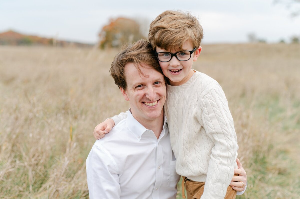 Dad and son with arms around eachother, smiling at photographer, Abby Park Photography