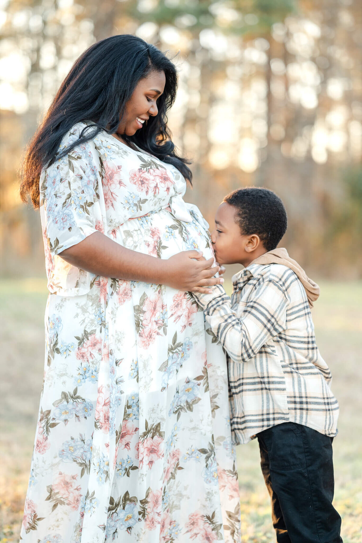A young boy kisses his mom's pregnant belly during a Chesapeake maternity photography session.