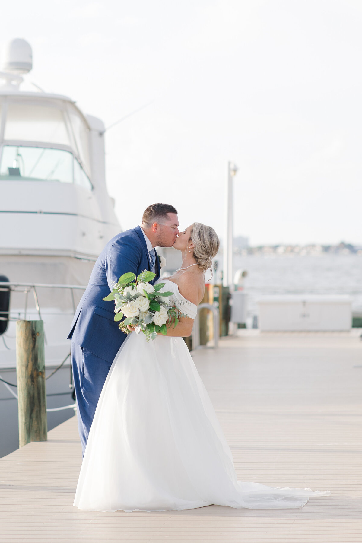 groom kissing bride at coastal wedding