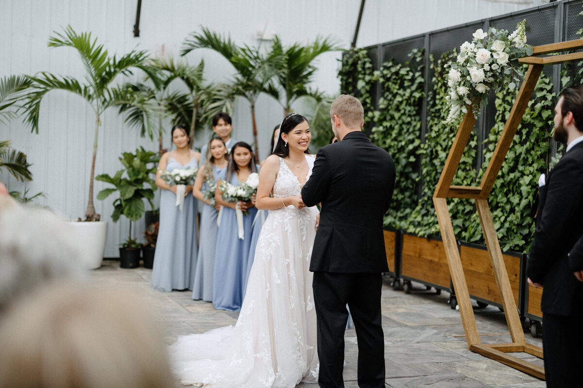 Bride and bridesmaids smiling as they listen to the groom's vows during the wedding
