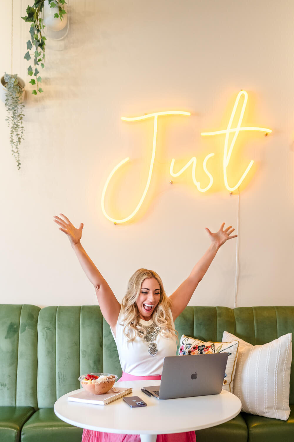 Female entrepreneur celebrating while working on laptop in stylish cafe.