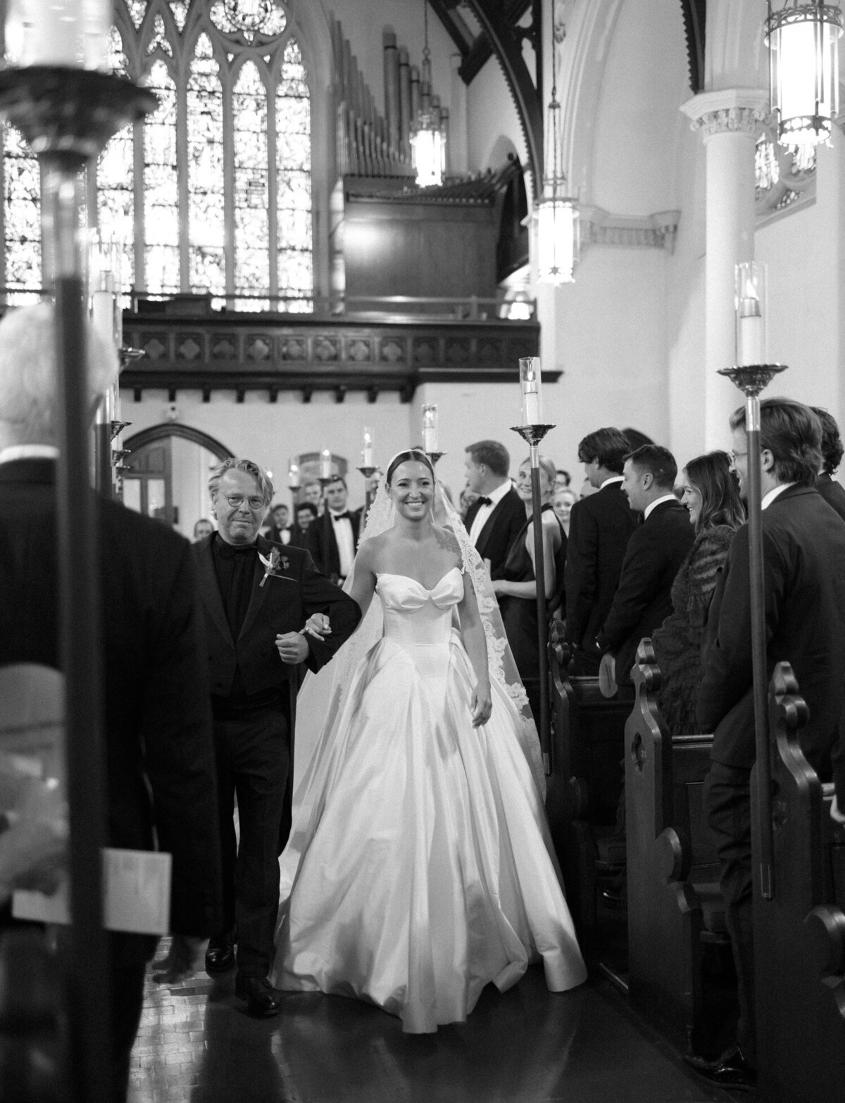 A bride in a lace cathedral veil walks down the aisle for her wedding ceremony at Christ Church, Detroit