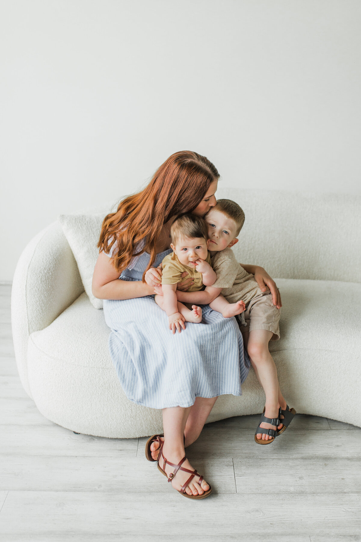 Mother sitting on a couch with two young children, hugging