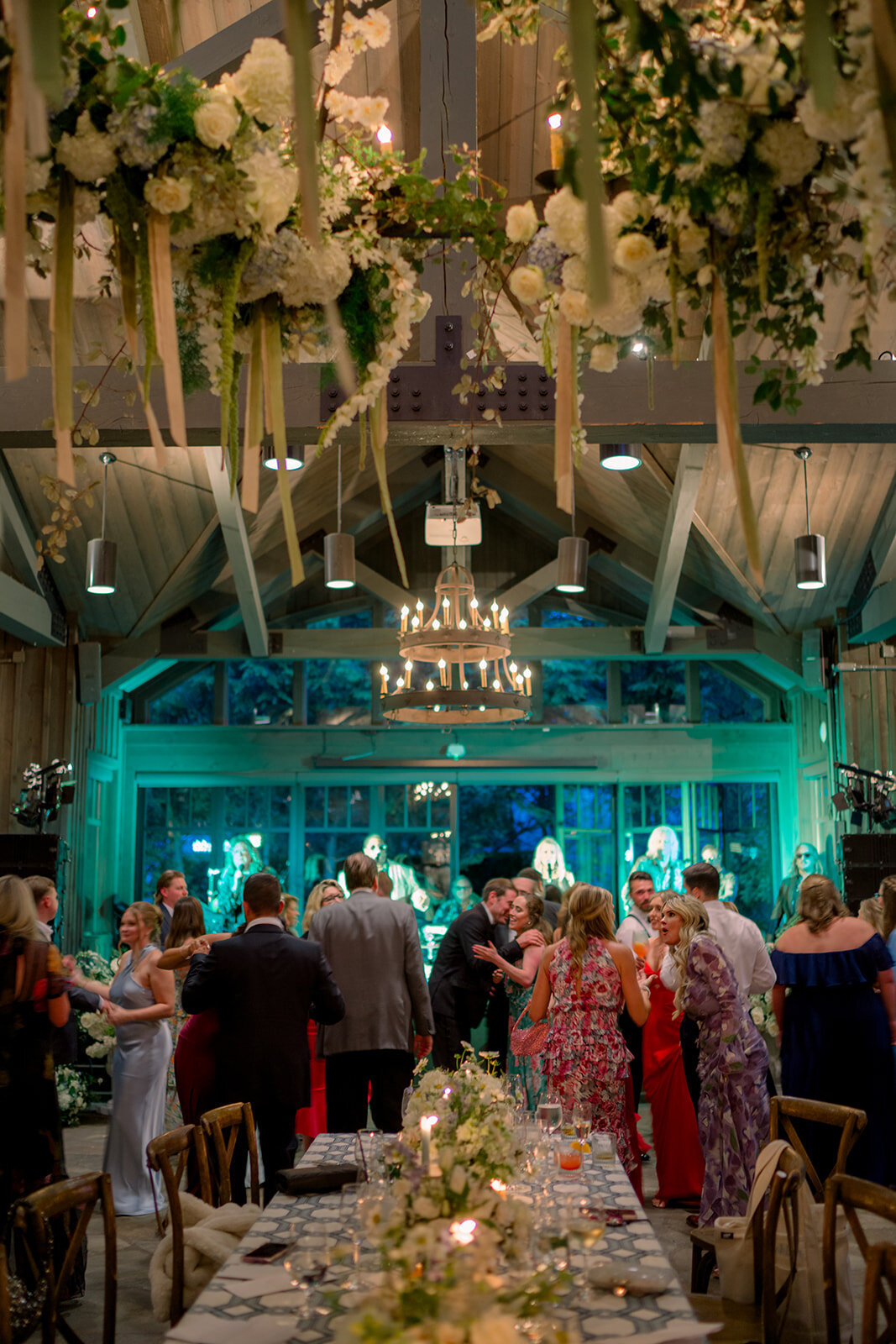 Wedding reception at a Highlands, North Carolina venue with guests dancing beneath elegant hanging floral chandeliers and candlelight.