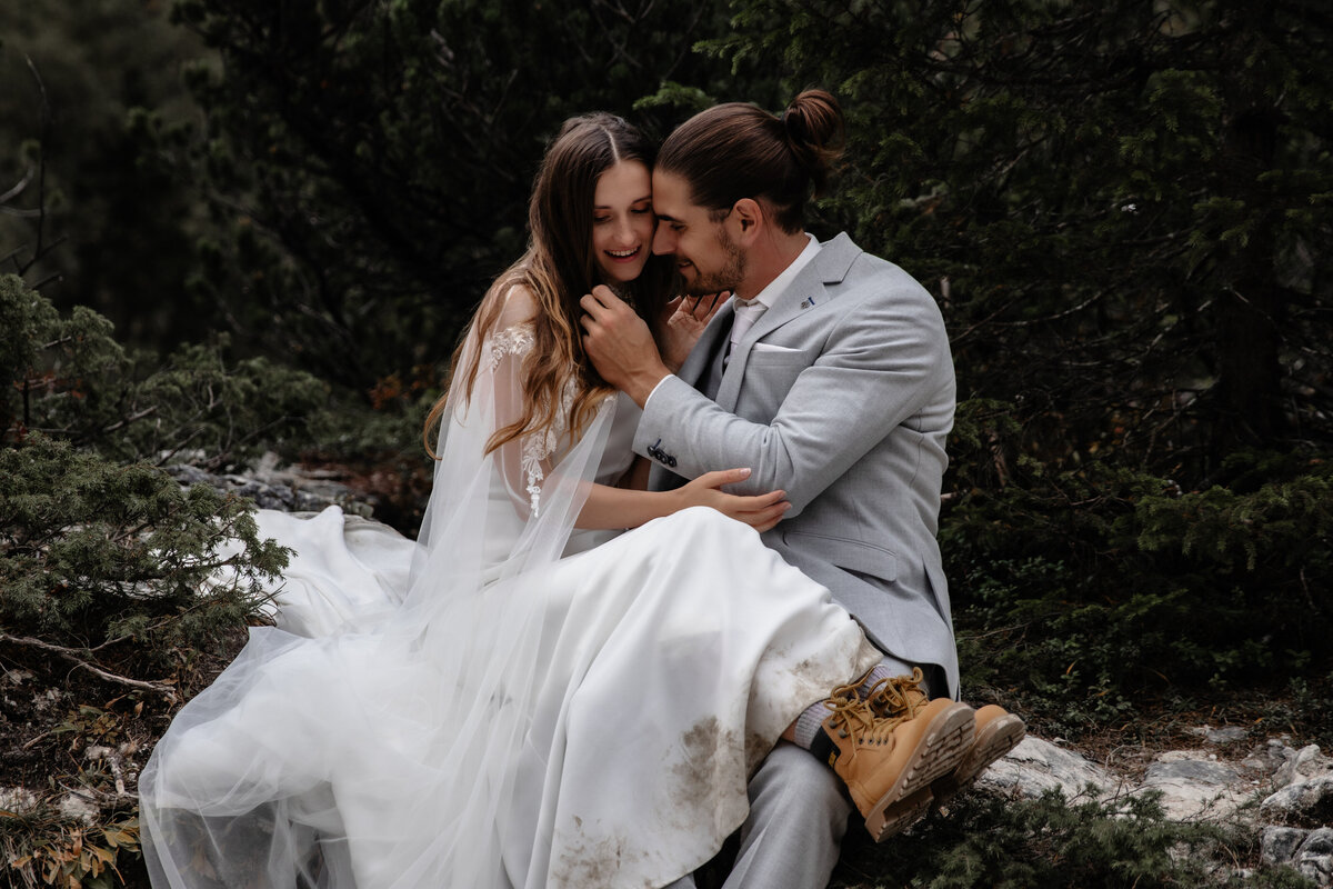 Elopement wedding couple posing on a cliffside with dramatic mountain views