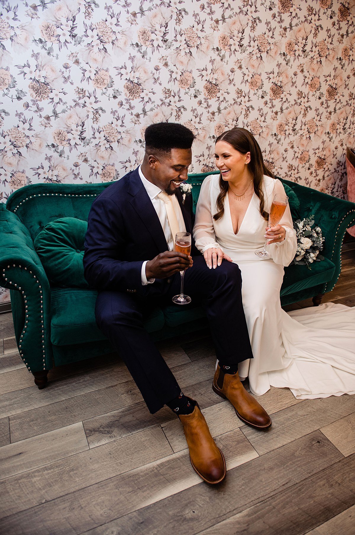 Couple drinking champagne and sitting on a green couch inside of Murfreesboro wedding venue