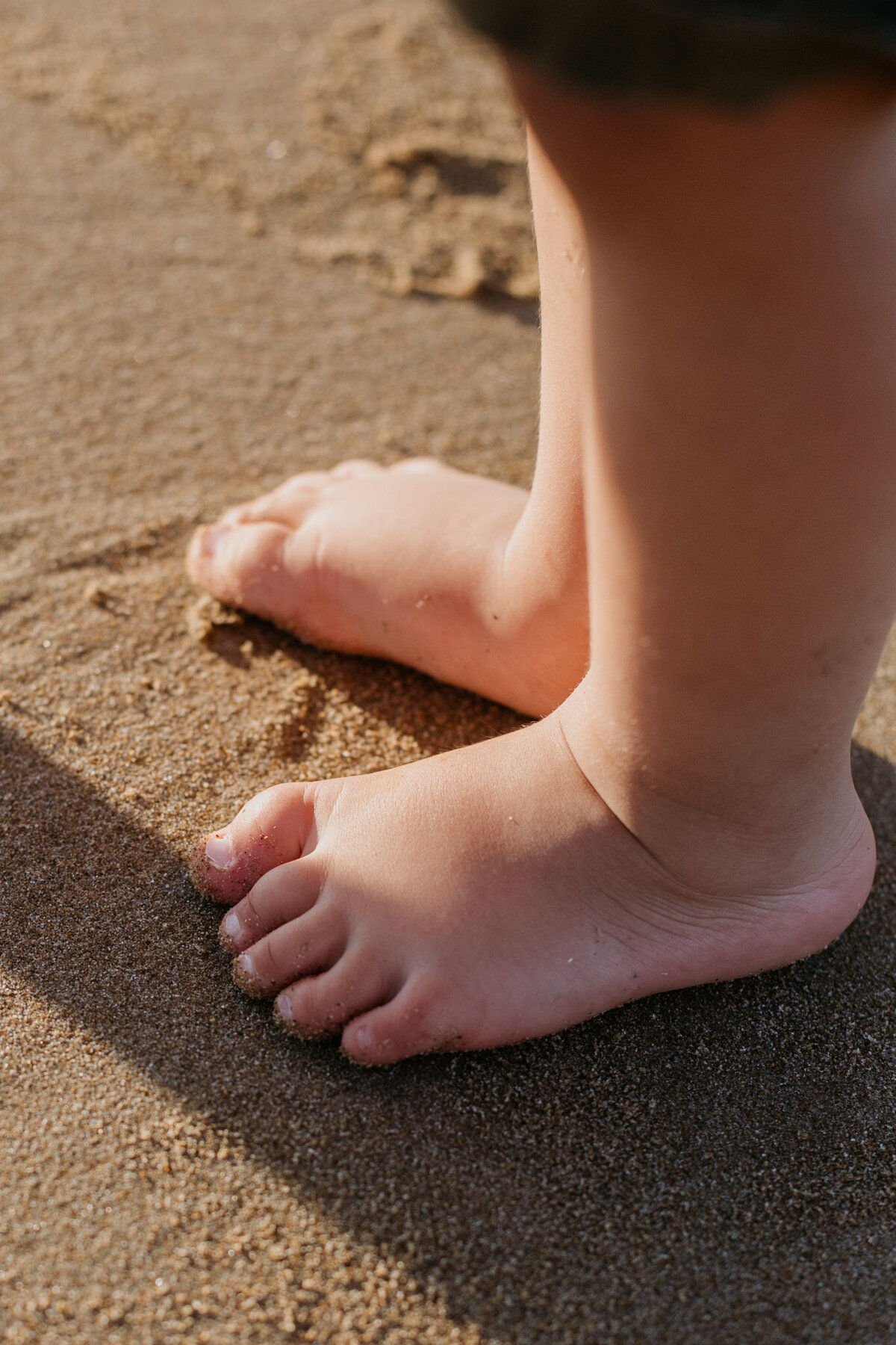  Close-up of a baby’s toes gripping the sand, capturing a cute moment.