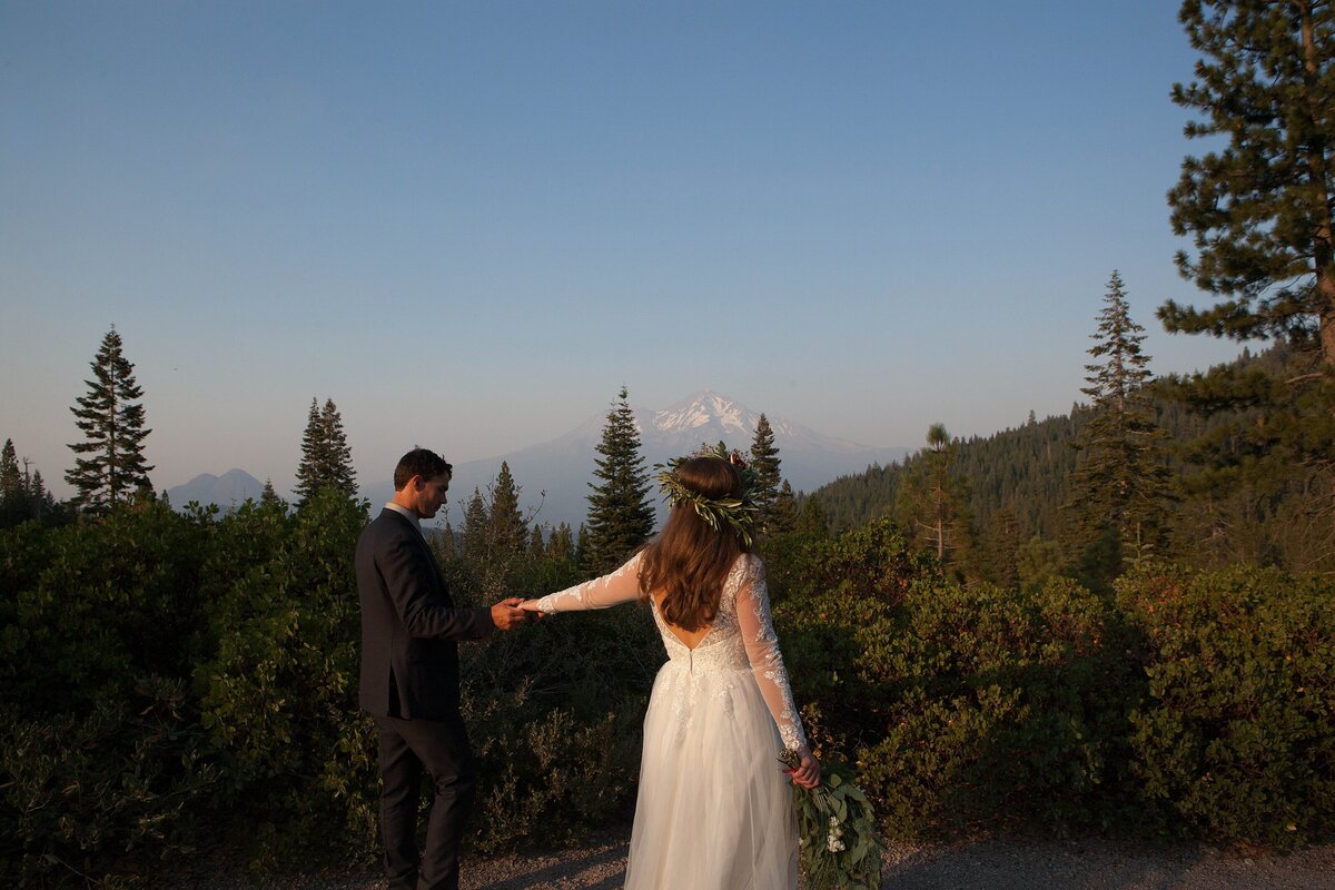 eloped newlyweds holding hands looking at Mt Shasta