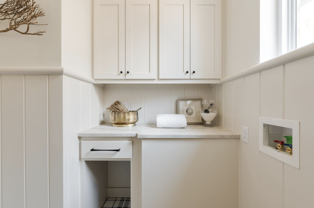 Neutral laundry room with vertical paneling, cream cabinetry.