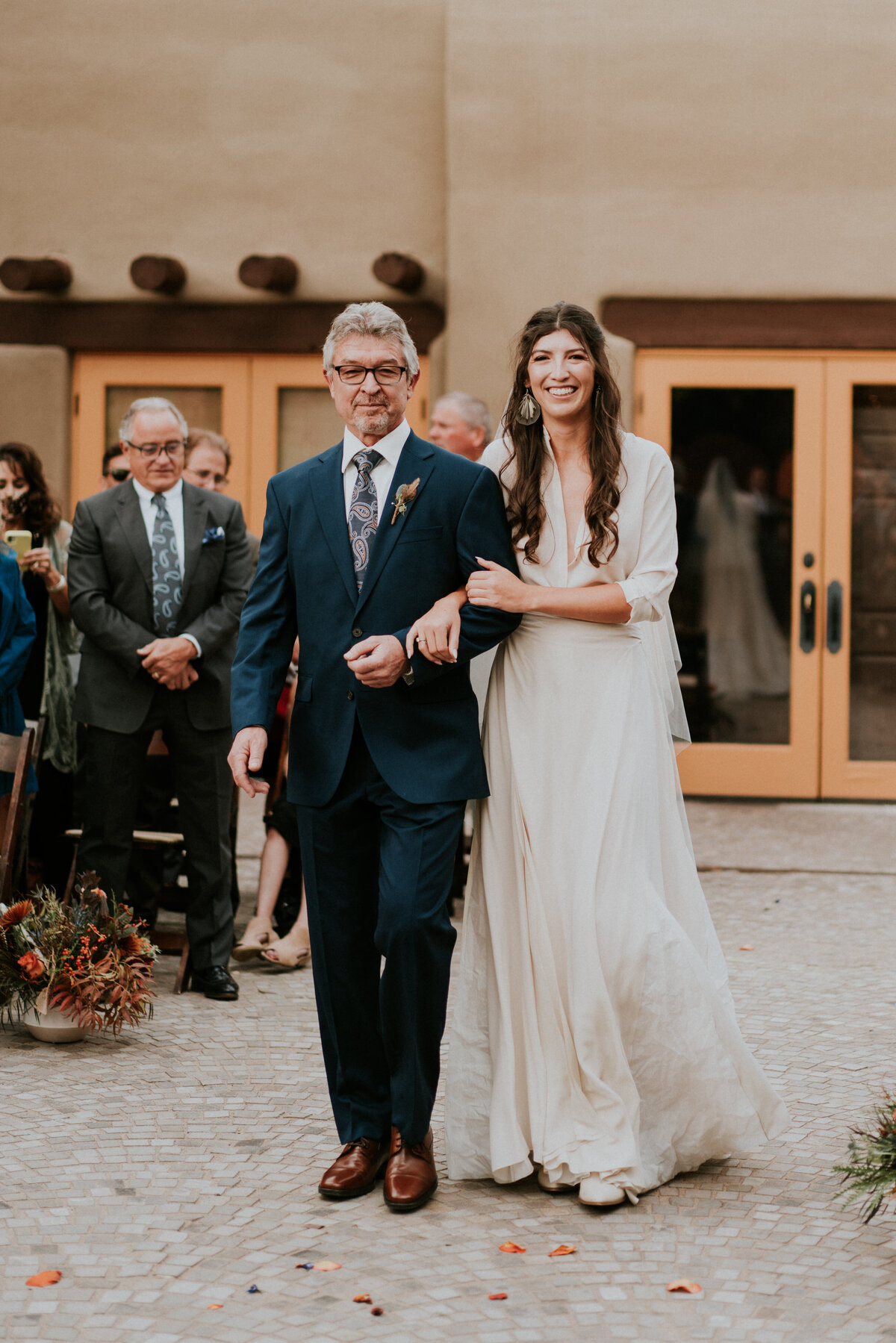 Bride walks down the aisle with her father during the ceremony on her wedding day.