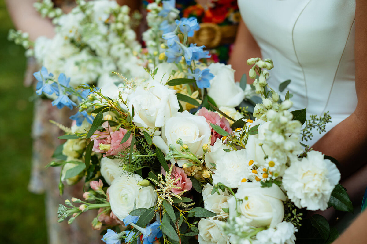 Close up of bride's wedding bouquet with baby blue, pink, and white flowers
