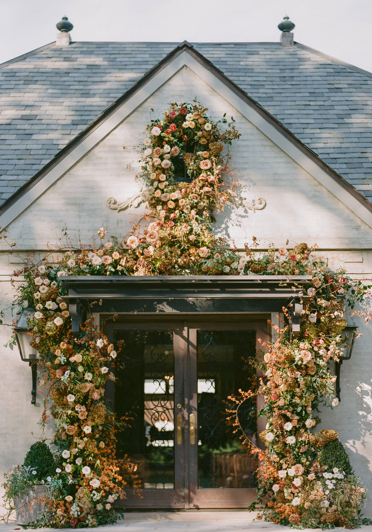 Organic growing floral installation for fall wedding ceremony backdrop. Private residence wedding build out for outdoor wedding ceremony and reception. Whimsical and organic floral design for autumnal wedding in colors of copper, yellow, blush, cream, and pops of orange. Clear tented wedding outside Nashville, TN. Design by Rosemary & Finch Floral Design in Nashville, TN.