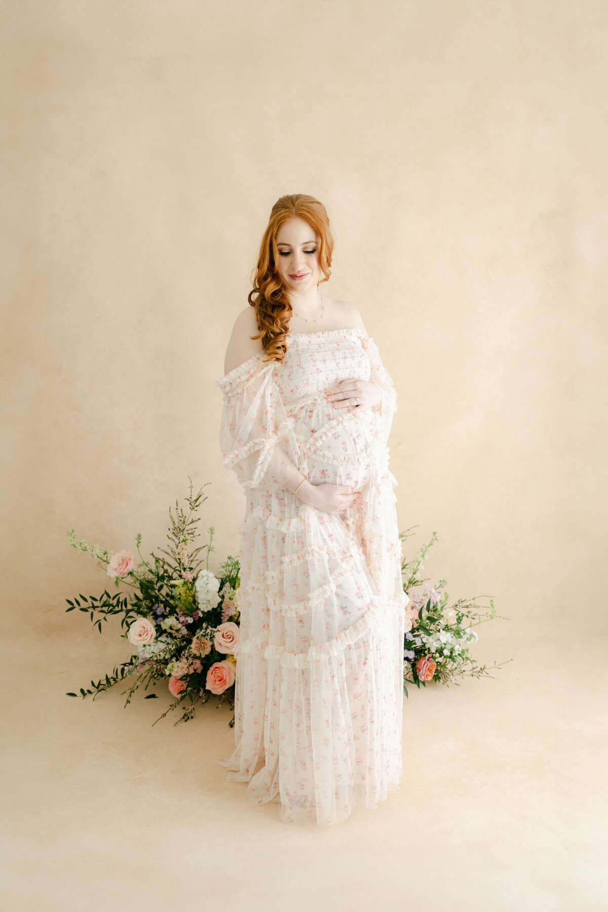 a pregnant woman standing in front of a flower arrangement