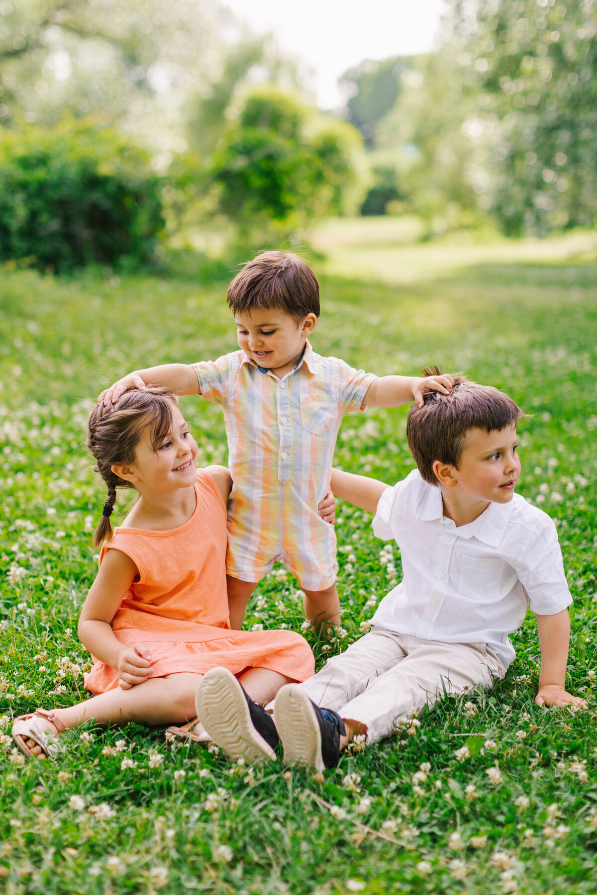 Three kids sitting together in a grassy field