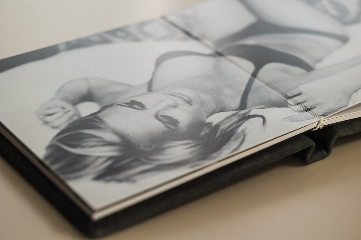 A black and white print in a black leather boudoir album.