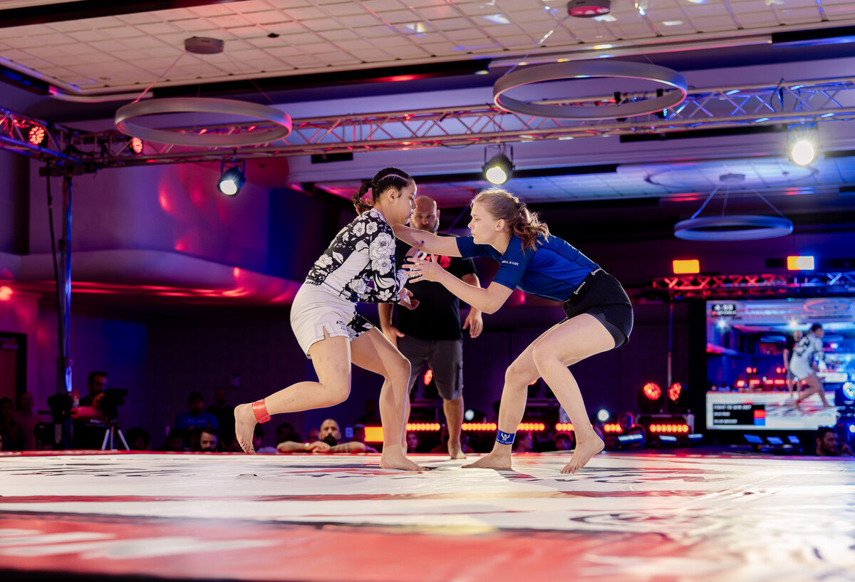 Two girls grappling on their feet at Fight to win on stage.