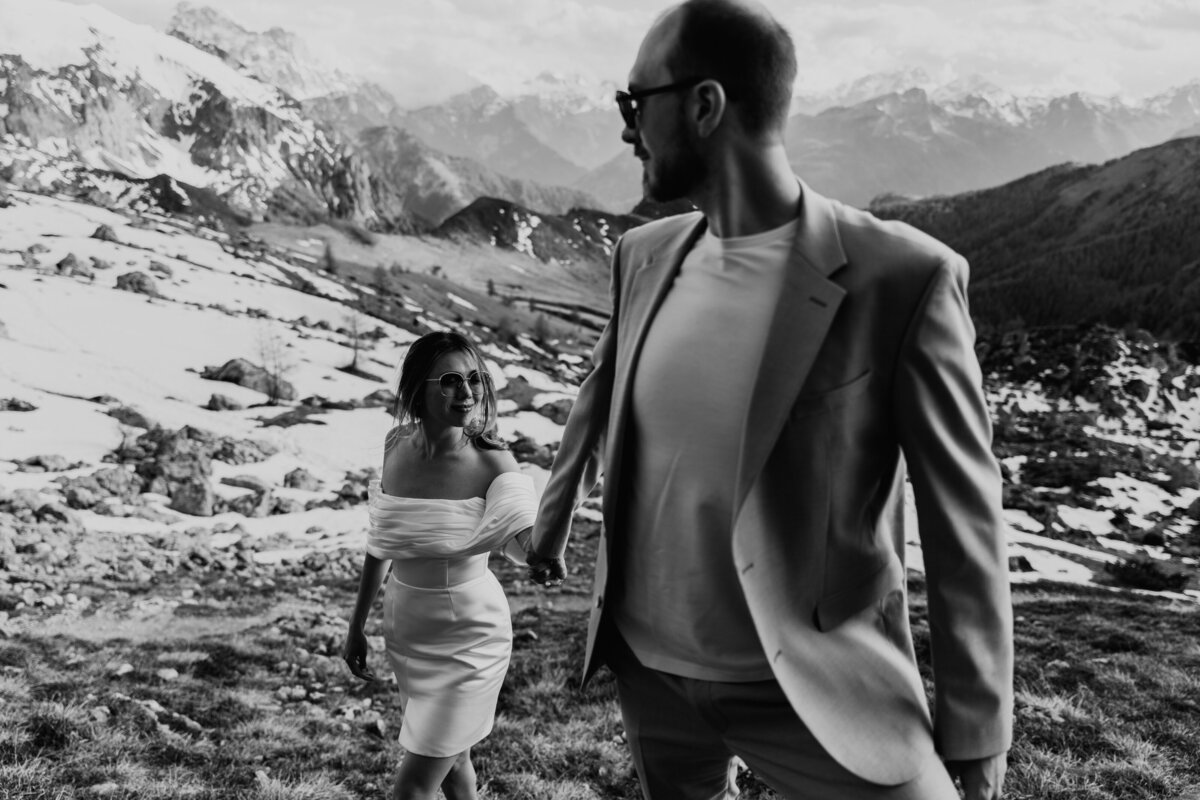 Bride and groom hiking together along mountain ridge