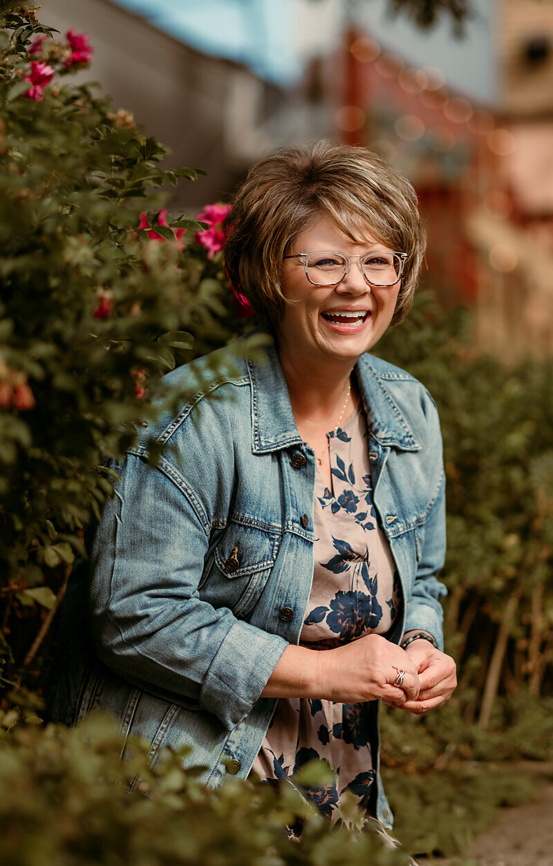 After image of client laughing outdoors among flowers, showing genuine confidence and warmth captured during her Shannon Kathleen Photography online dating session.