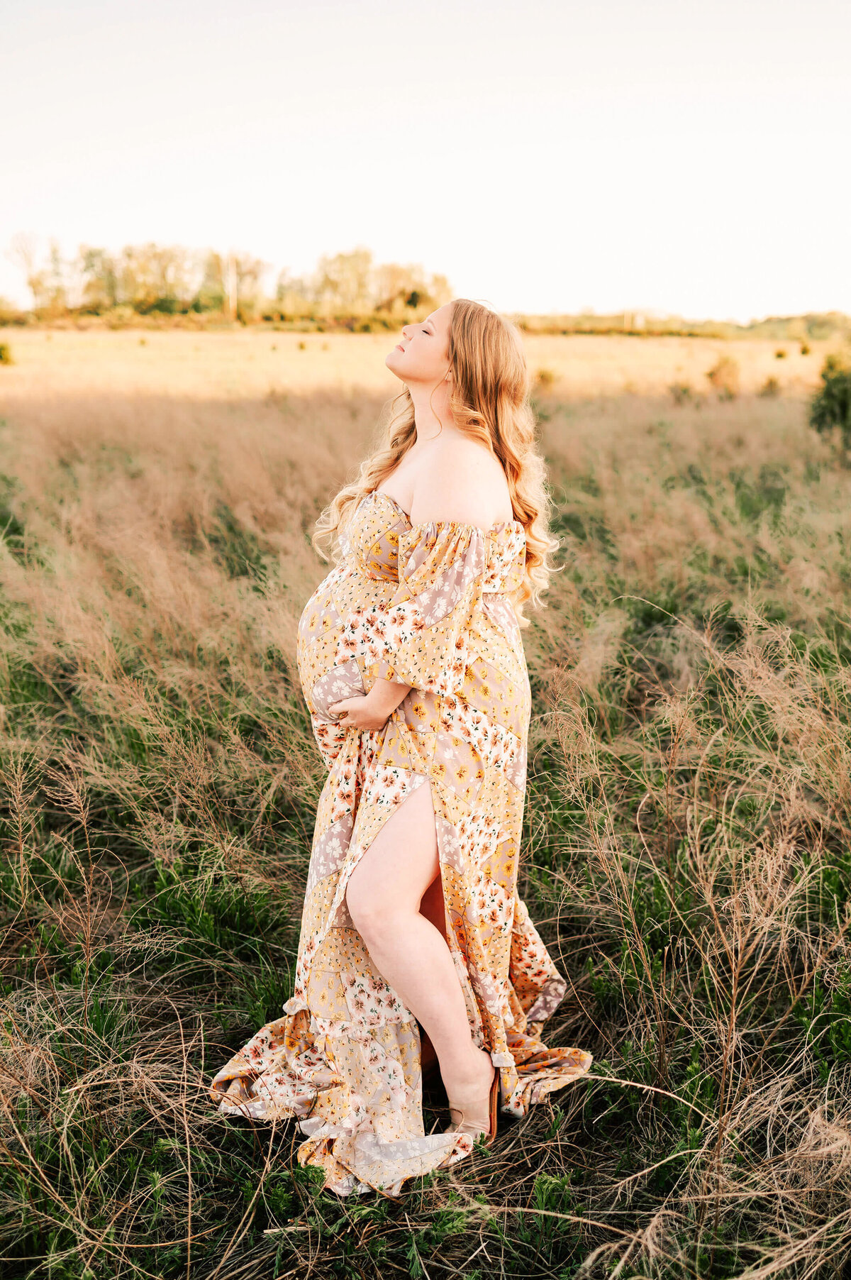 pregnant mom with red hair in floral dress relaxing during Springfield MO maternity photography session