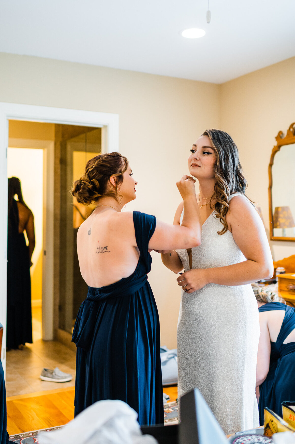 maid of honor helping bride in their bridal suite with her make up as they get ready the morning of the wedding