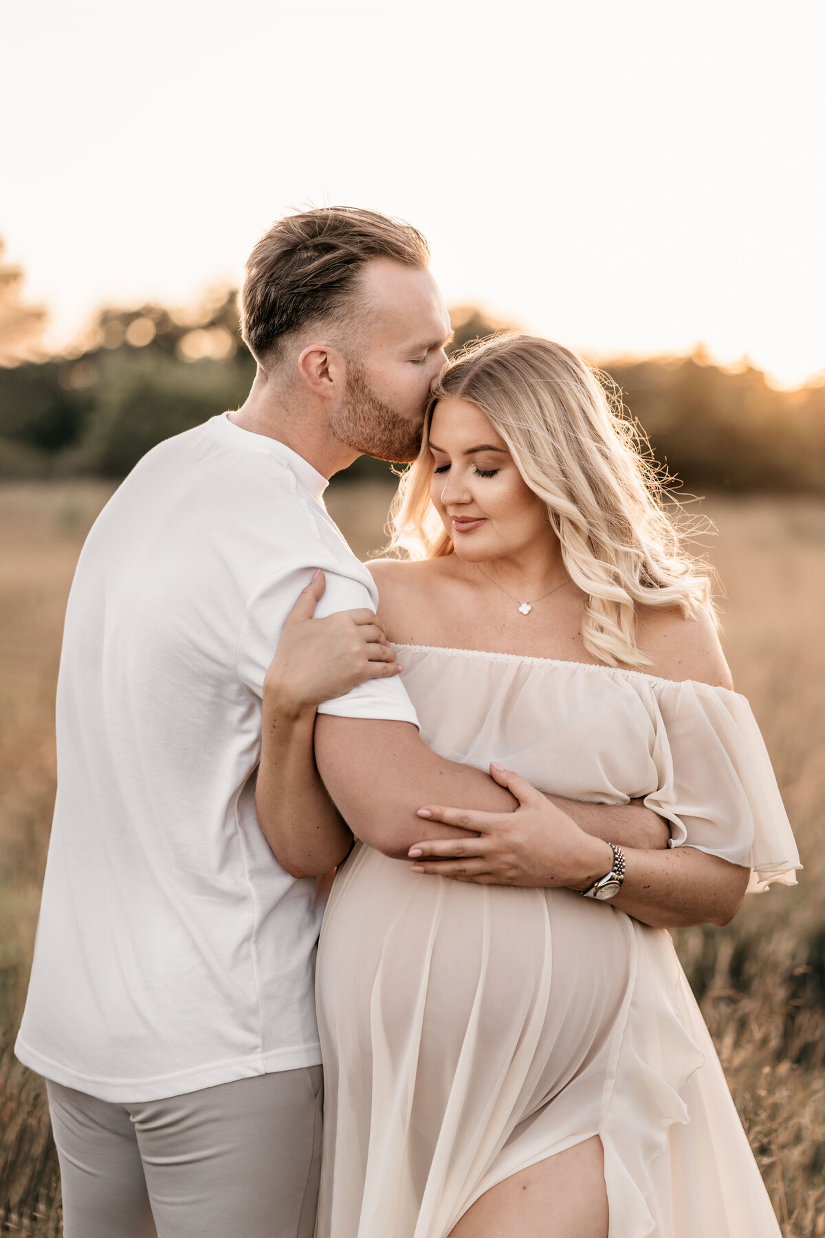 Photo of a pregnant woman and her husband at sunset
