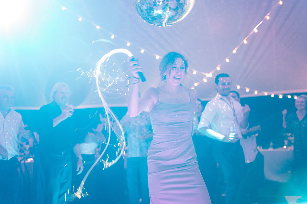People dancing under a tent during a wedding disco dance party.