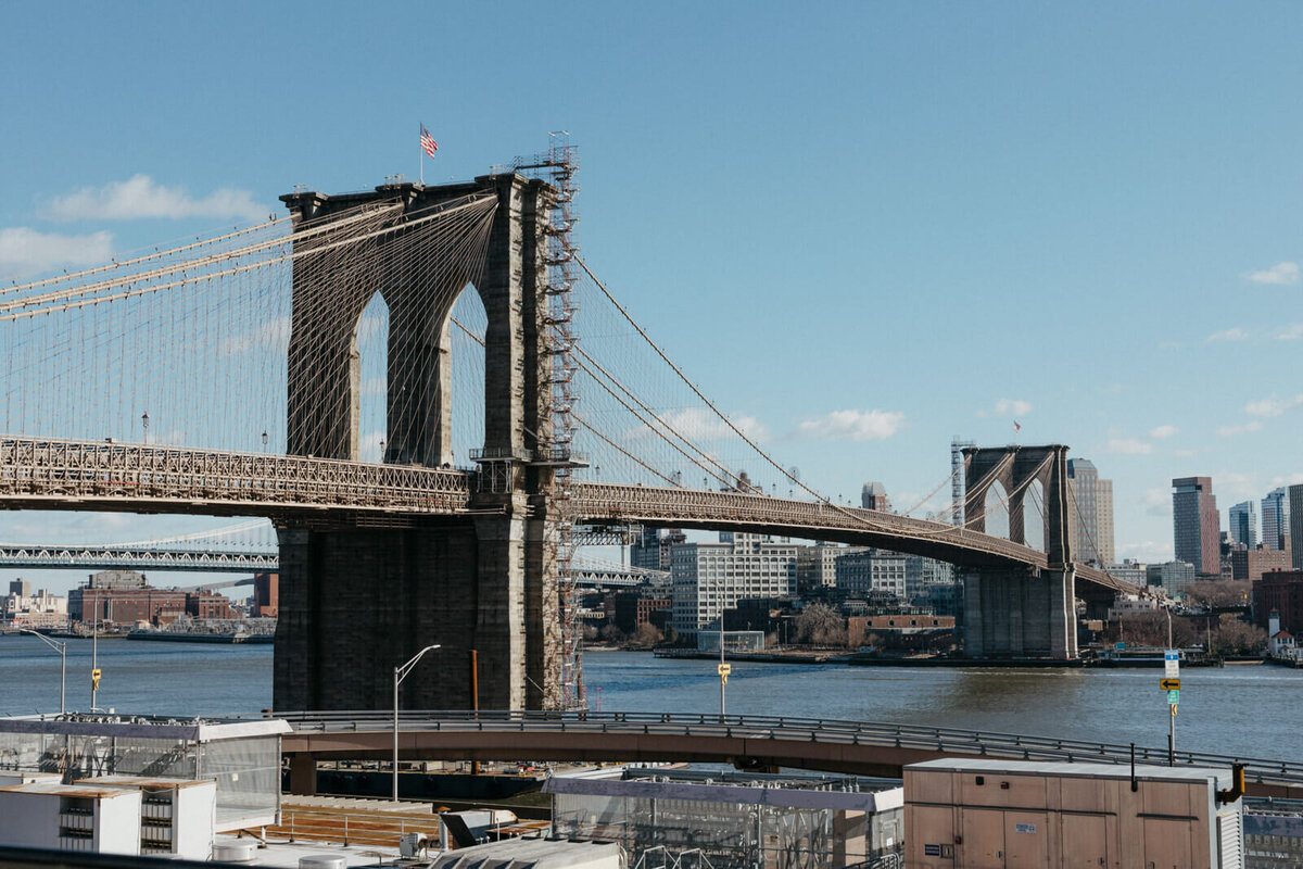 The Brooklyn bridge, a small bridge at the bottom, and many buildings in the background