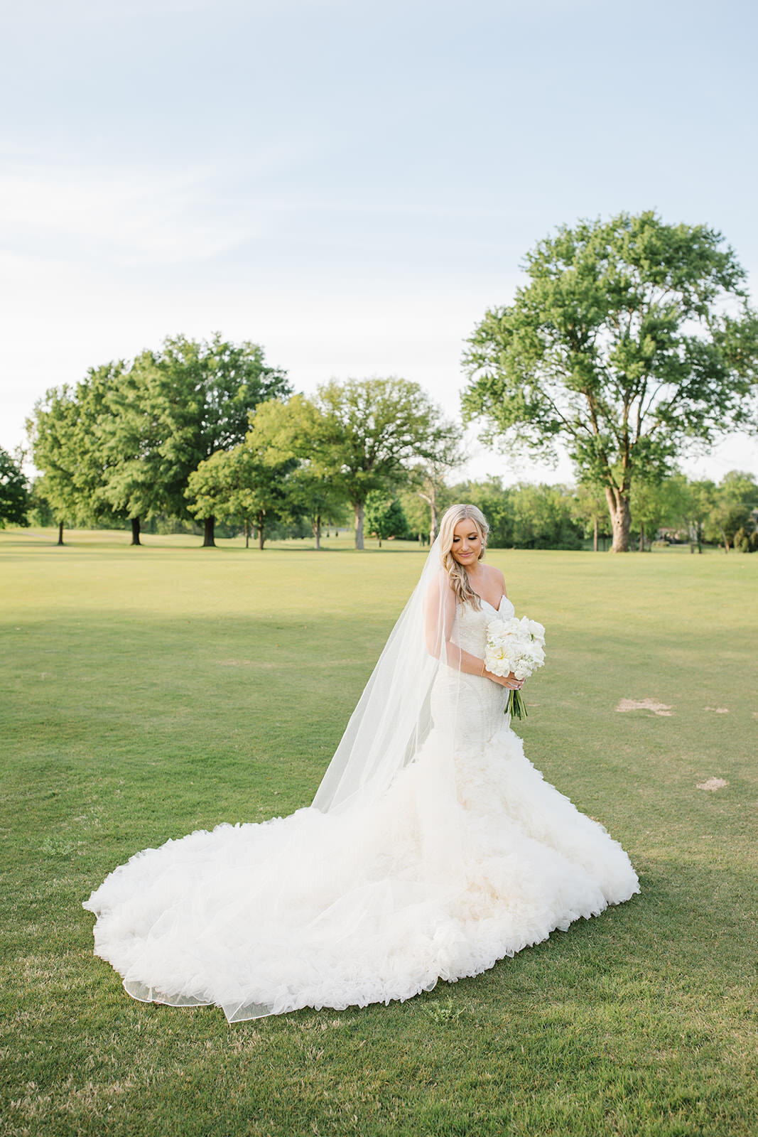 bride carrying a all white bouquet in a ruffled dress