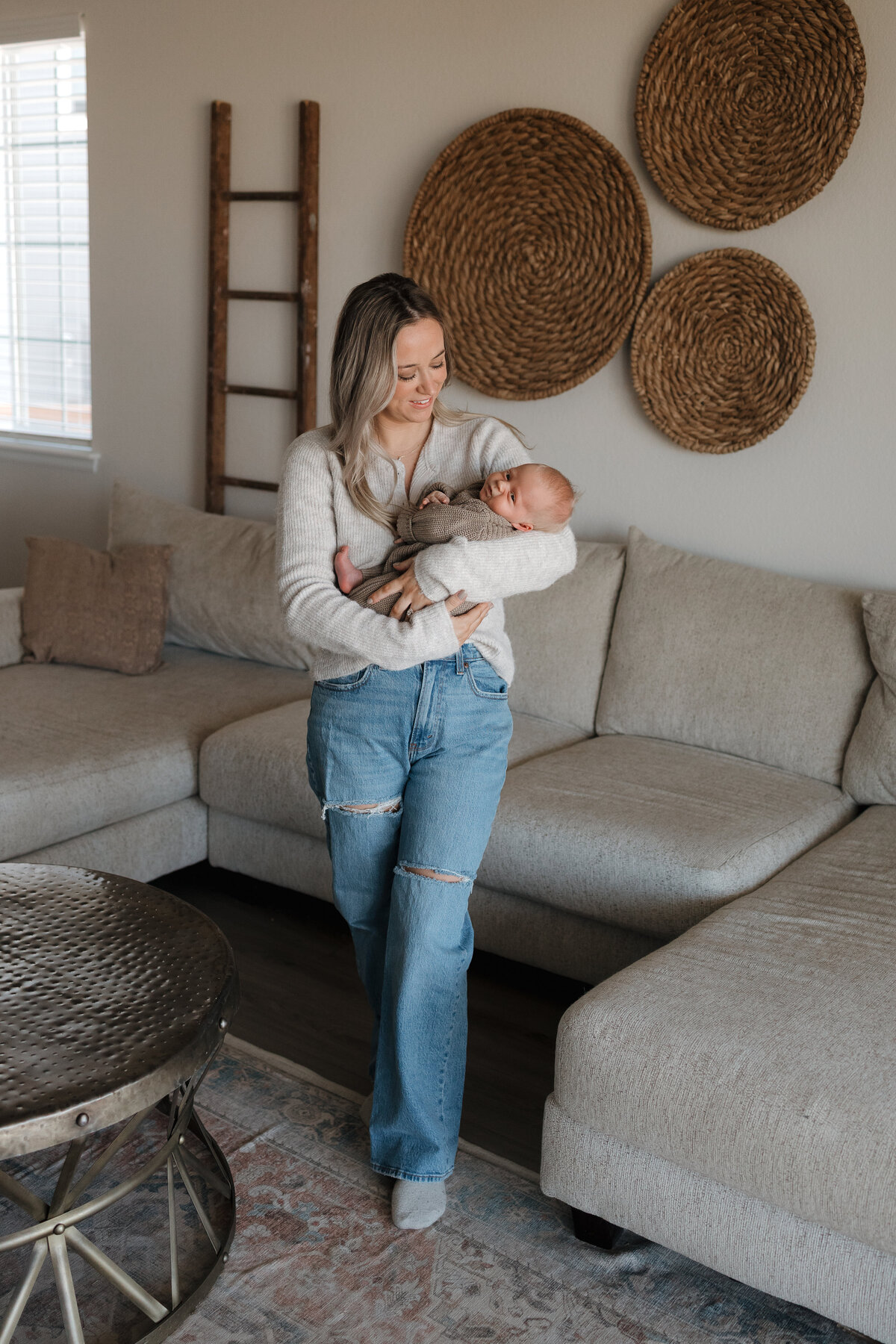 Longmont mom holding newborn in living room looking down and smiling