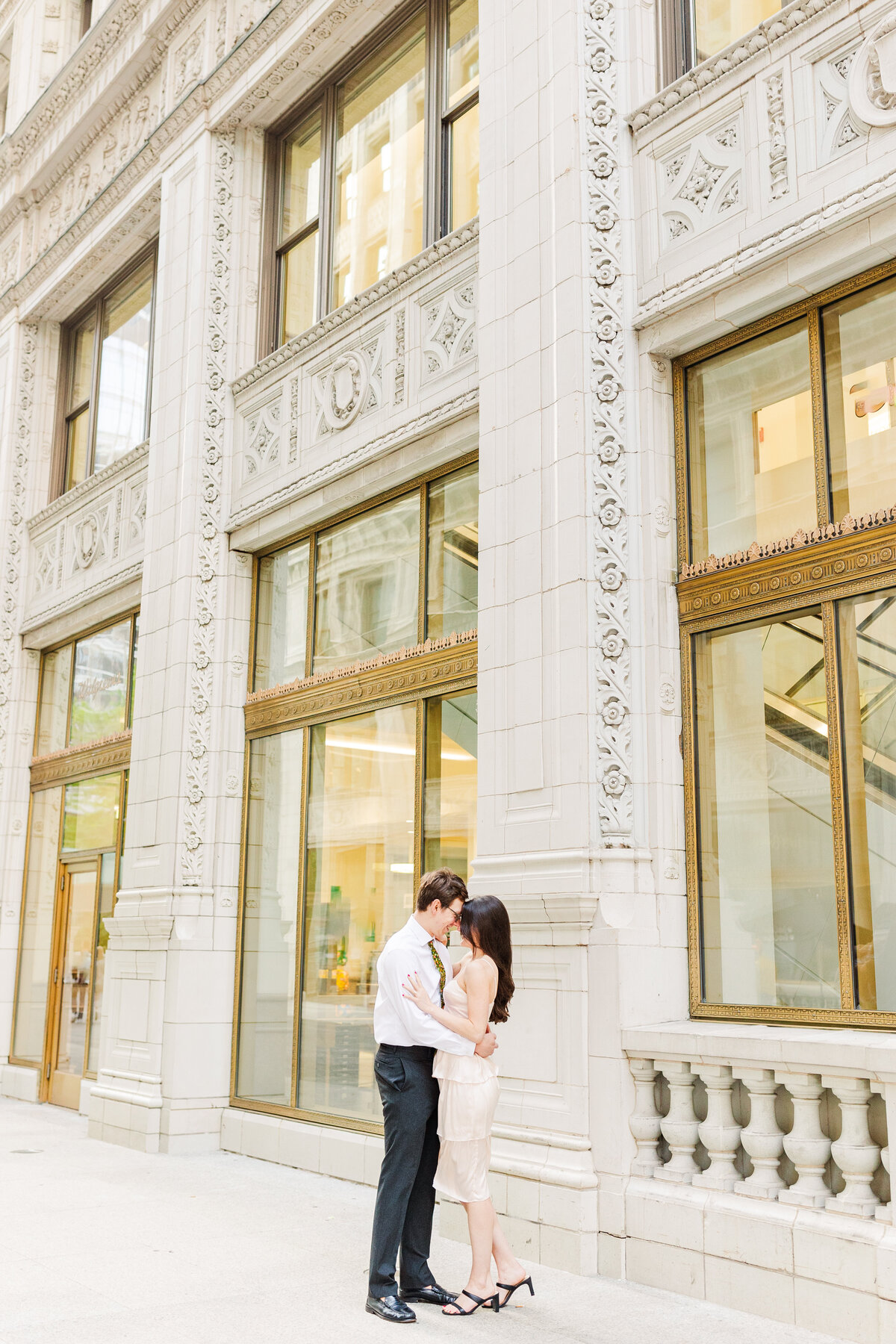 man and woman dressed up embracing in front of a building