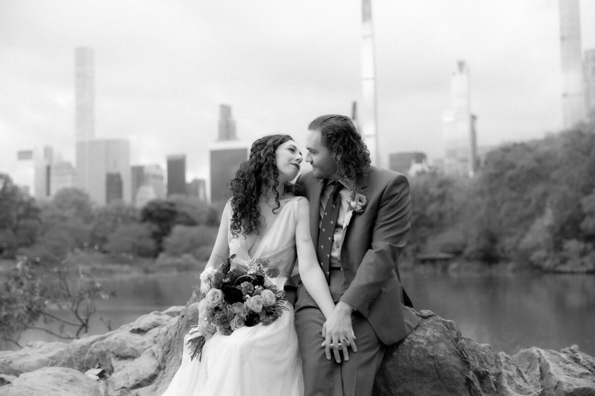 The couple standing close together surrounded by Central Park’s glowing fall foliage.
