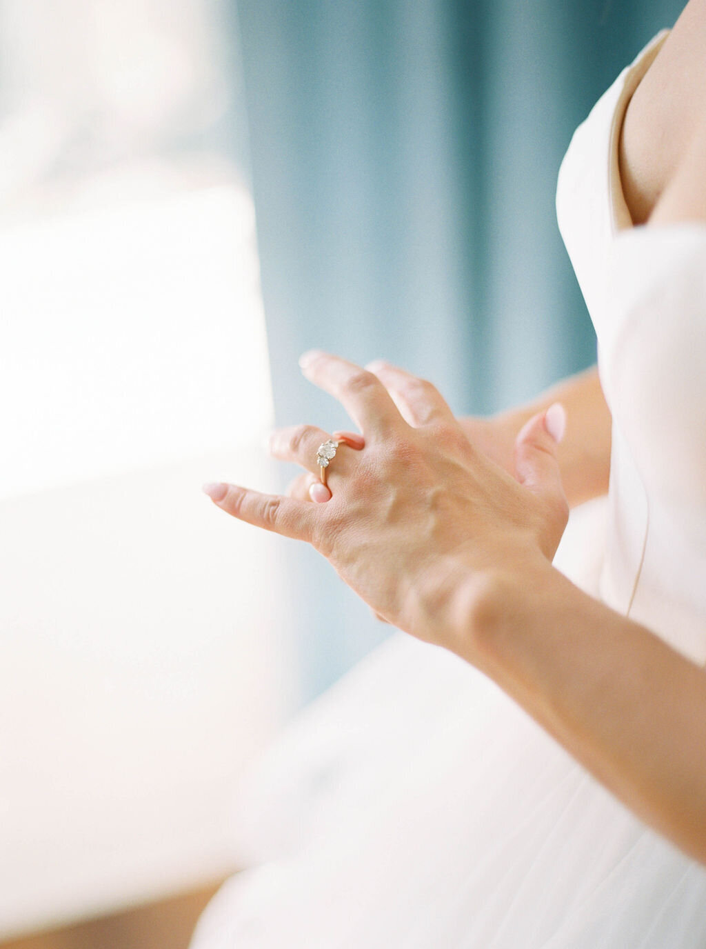 Wedding Photographer RI | A close-up of a bride's hands adjusting an elegant diamond ring on her finger. 