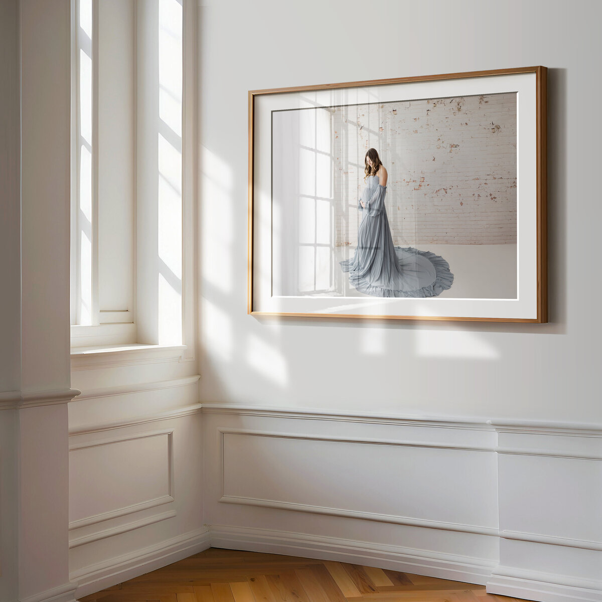 framed artwork on white wall of pregnant mother in blue maternity gown