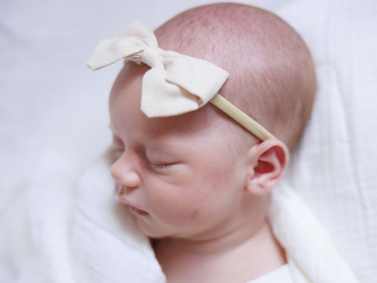 baby's face in bow headband for Tampa newborn photographer Tina Marie Studio.