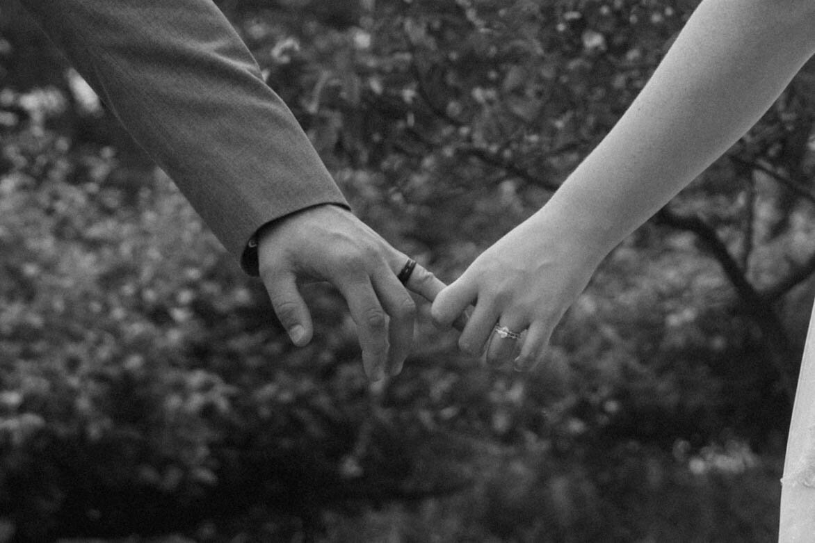 Detail shot of the bride and groom holding hands, showing off their wedding rings during portraits at The Blue Heron Barn.