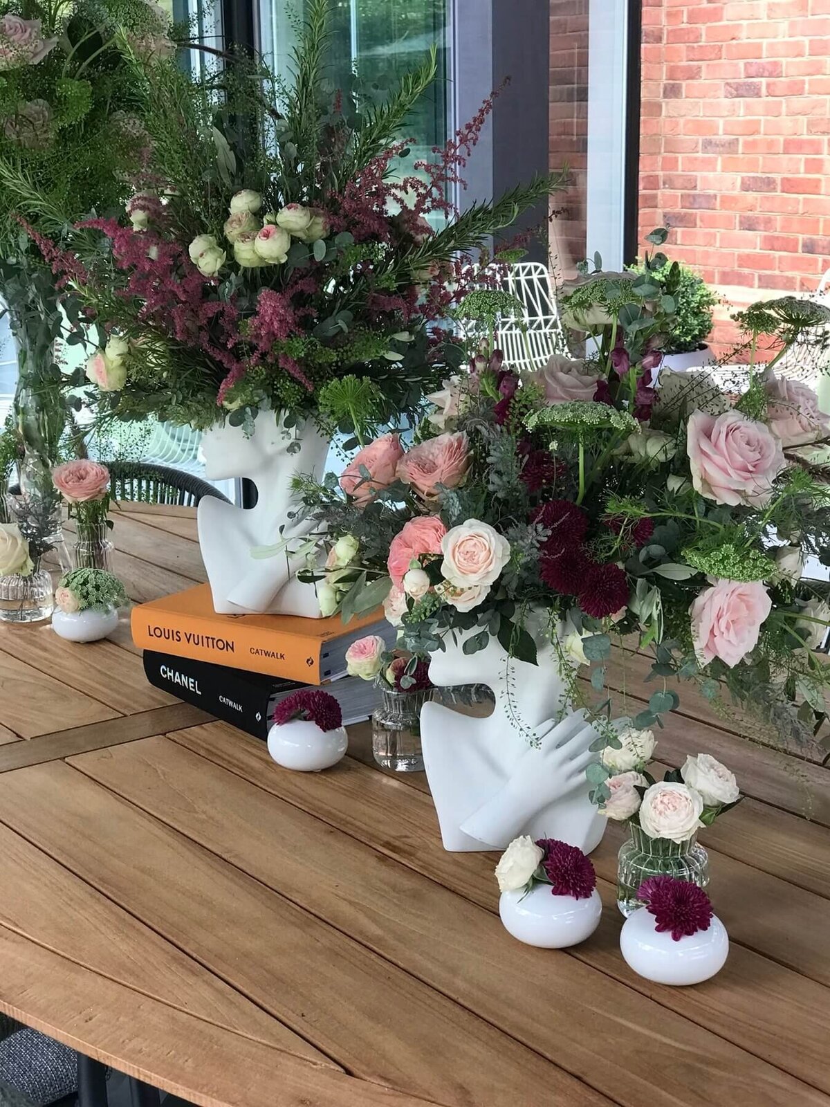 Flower arrangements in a white vase with small flowers sat on a wood table