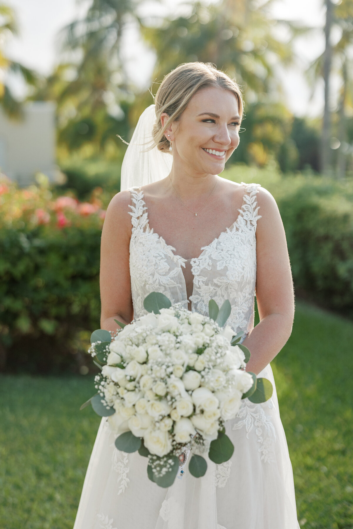Smiling bride holding a white rose bouquet in Cancun wedding, photographed by a Philadelphia wedding photographer.