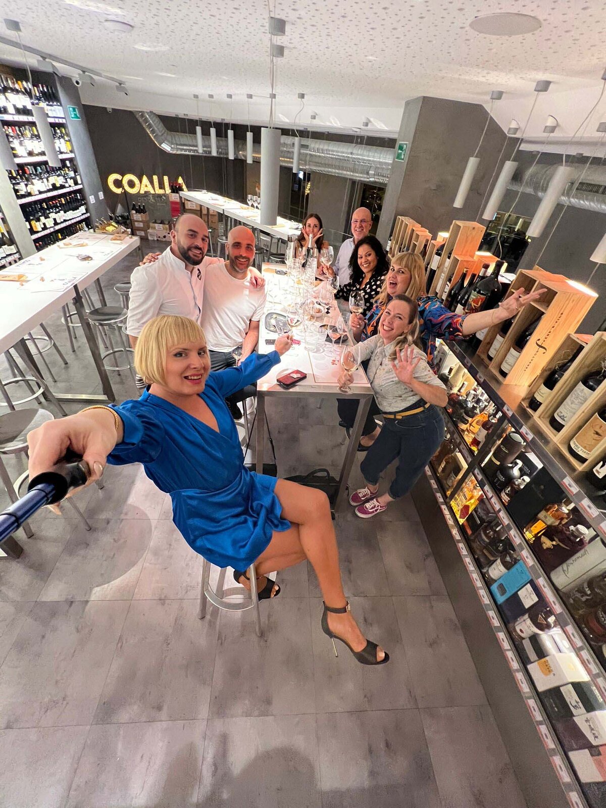 Cristina and a group of people posing for a photo and smiling while seated at a table at Coalla wine bar.