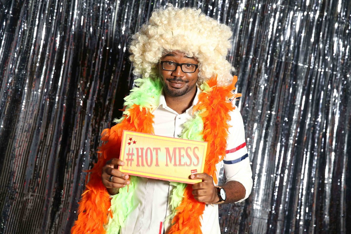 Man poses with sign while wearing a multitude of photobooth props. Photobooth by Ross Photography, Trinidad, W.I..