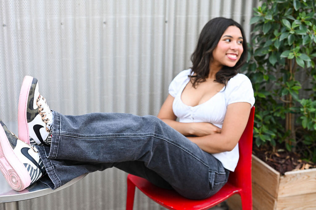 A girl sitting in a red chair with her feet up on a table.