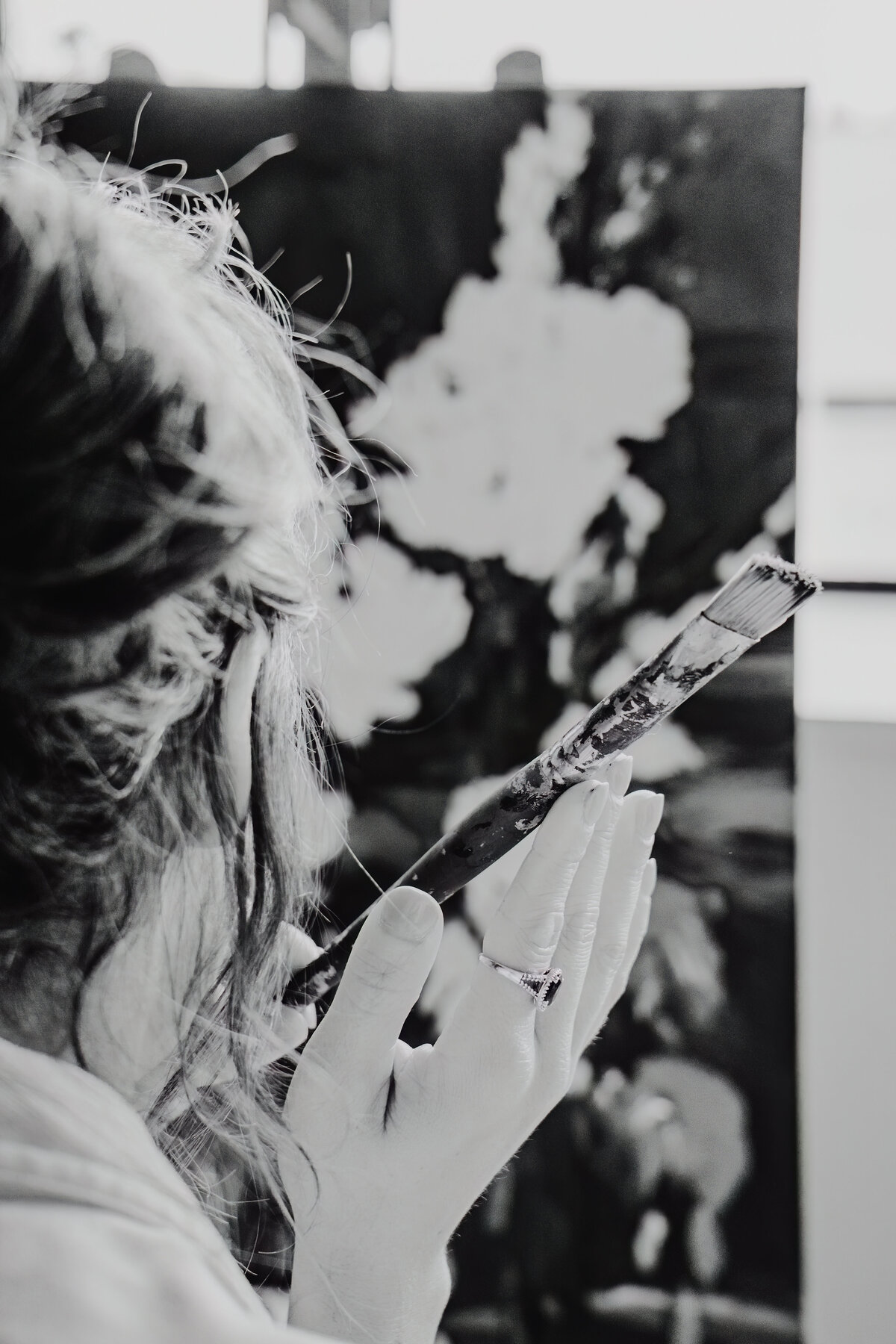 a painter, close up of  her looking at a painting with her paint brush in focus