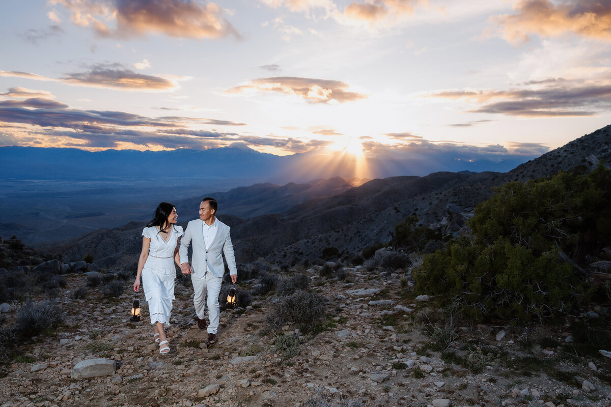 Joshua Tree elopement with bride and groom at Keys View walking hand in hand during sunset with lanterns.