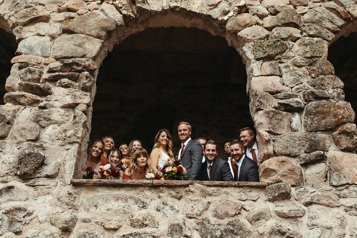 Bride and groom look through the rocks with their bridal party at Cherokee Ranch and Castle.