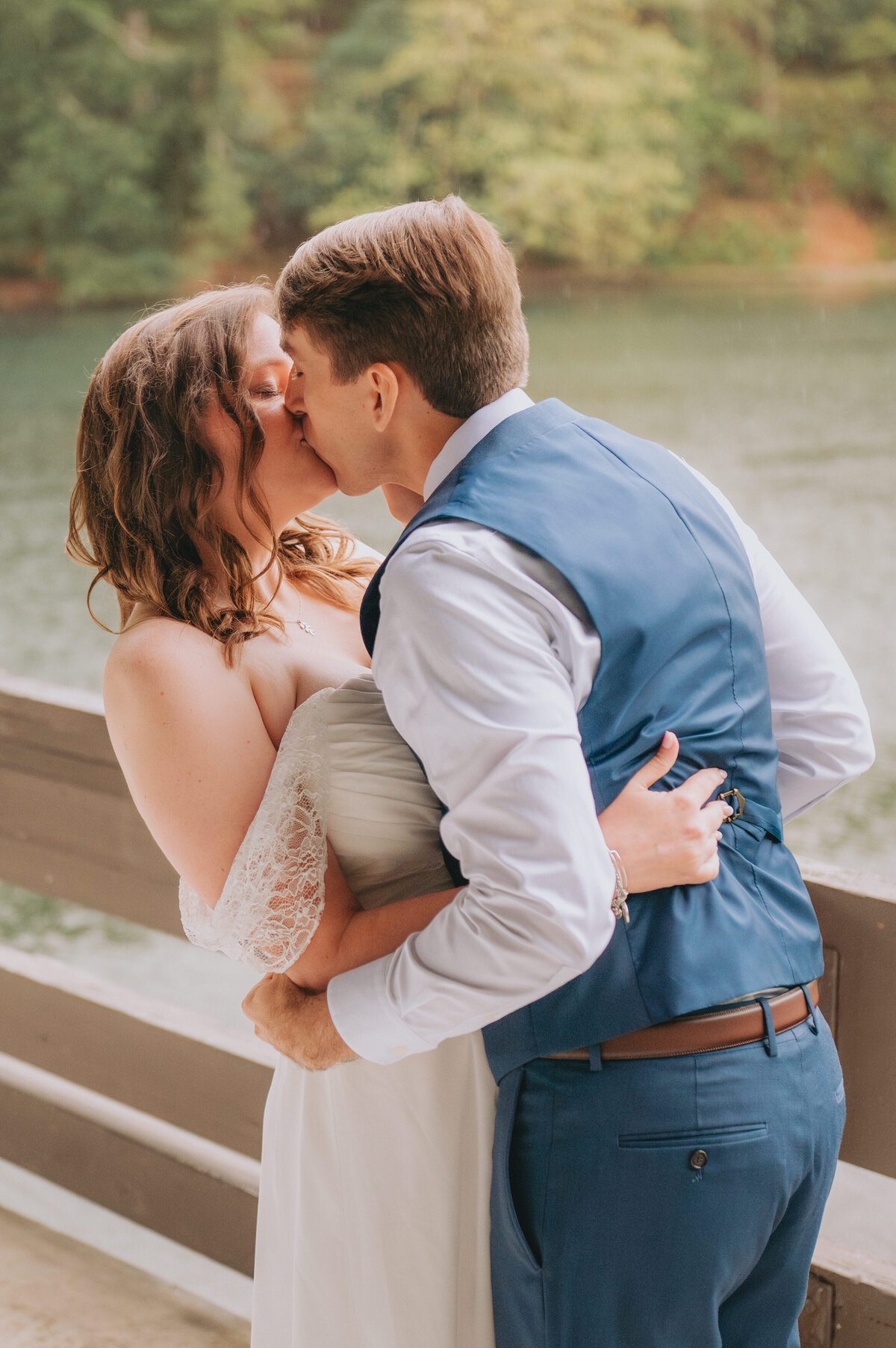 A couple leans in for a kiss next to a river